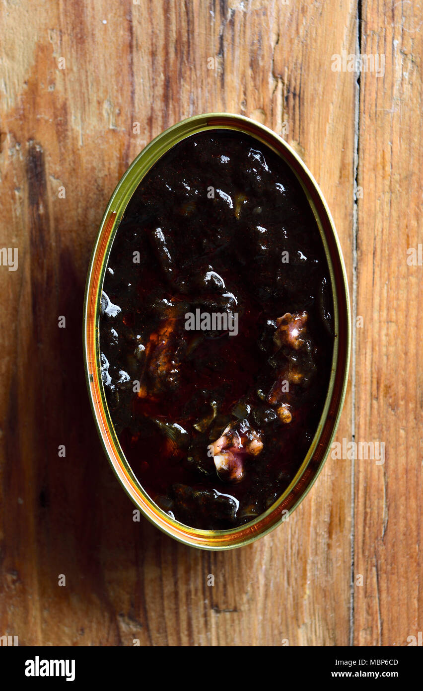 Una lattina di calamari al suo inchiostro su un tavolo Foto Stock