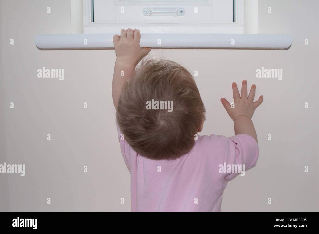 Un bambino raggiunge fino ad un davanzale per il supporto Foto Stock