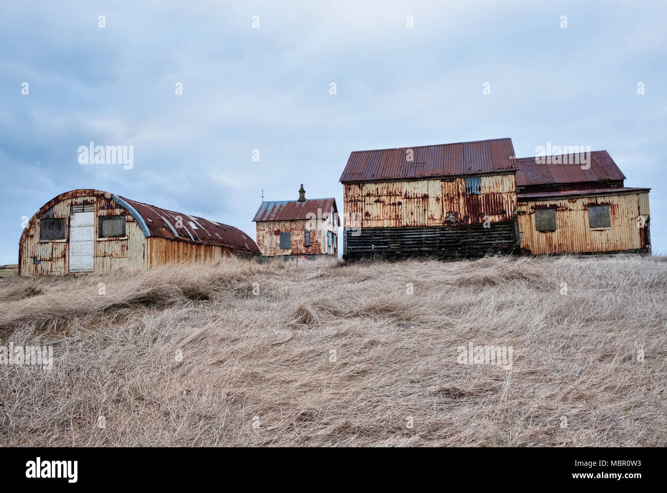 Nei pressi di Garður sulla penisola Reyjanes, Islanda. Corrugati vecchi edifici di ferro in un'azienda abbandonata sulla costa. Foto Stock