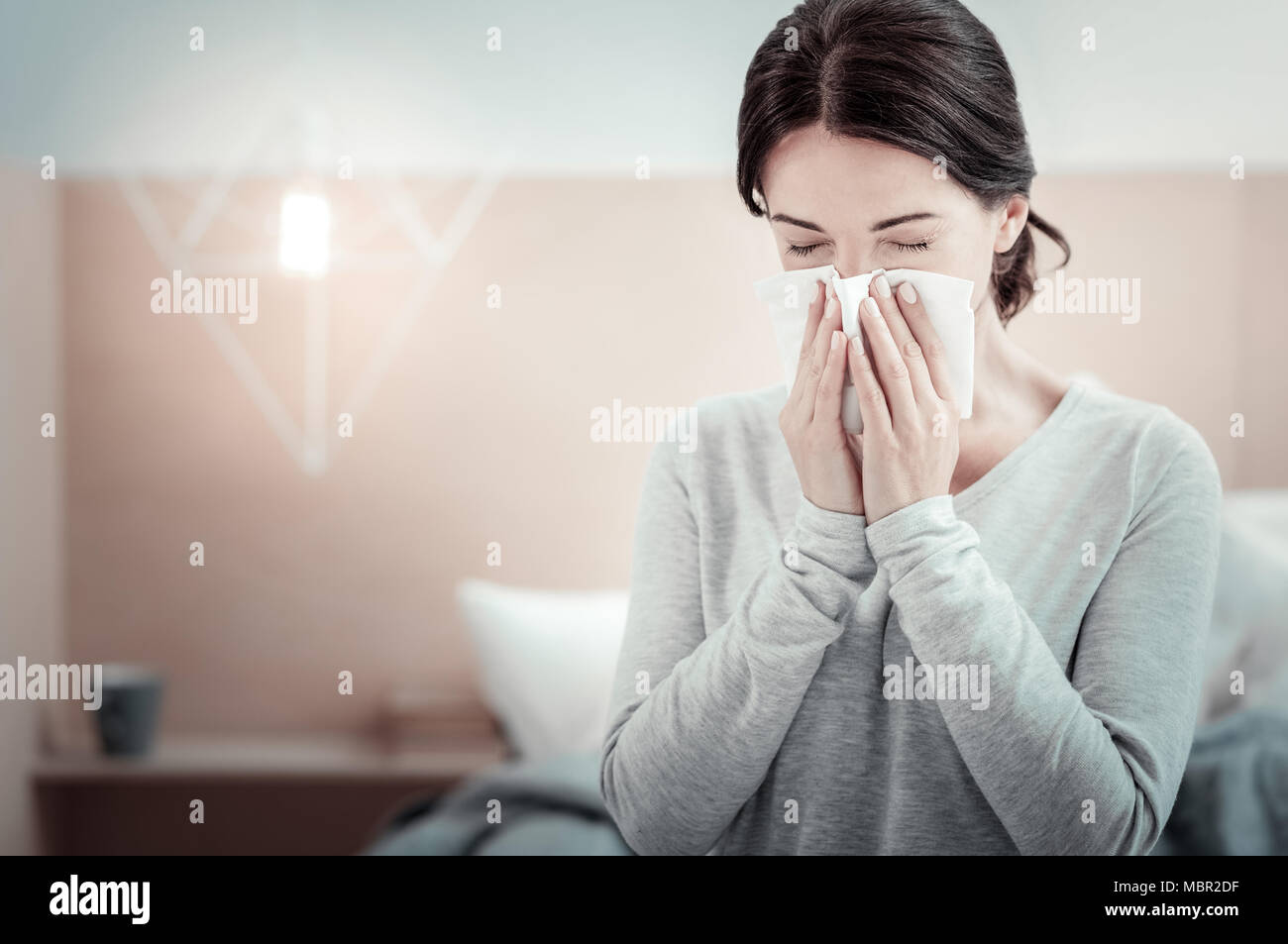 Ill triste donna starnuti e chiudendo gli occhi. Foto Stock