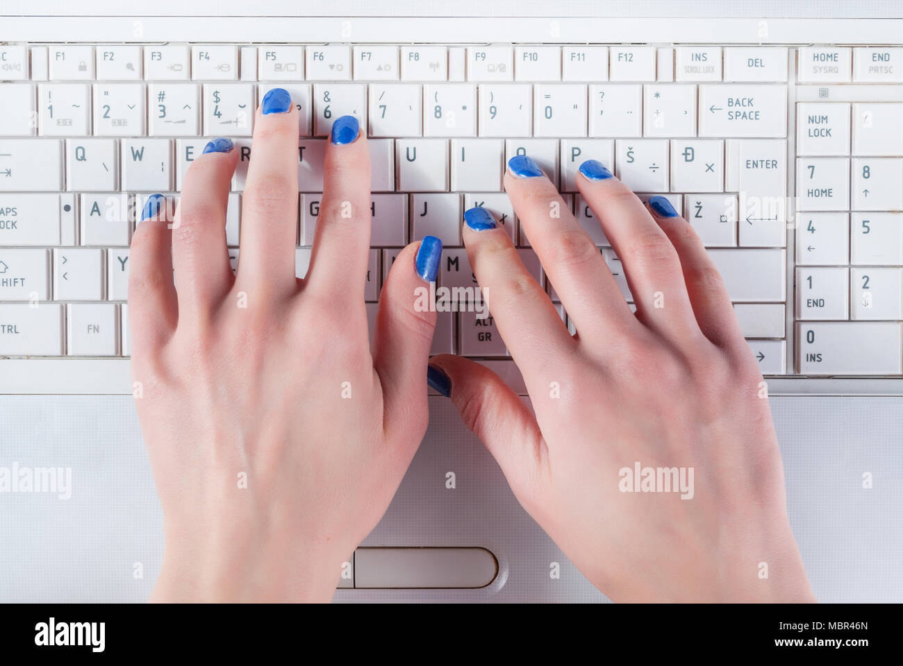 Donna mano lavorando su bianco tastiera portatile. Vista superiore, vicino fino Foto Stock