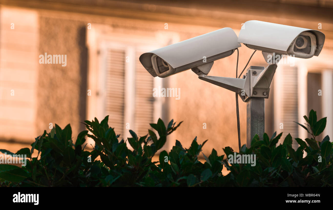 Due videocamere di sorveglianza su un recinto di fronte a una casa Foto Stock