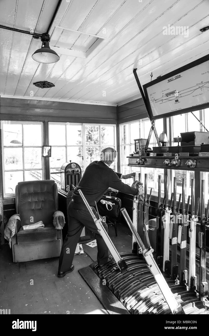 Foto d'azione in bianco e nero di un signalman che lavora isolato all'interno di leve di trazione vintage signal box, Severn Valley Railway. Heritage Railway Regno Unito. Foto Stock