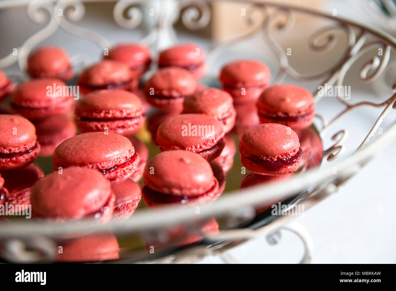 Primo piano di un buffet di nozze, un vassoio a specchio con little red macarones in un riser vintage Foto Stock