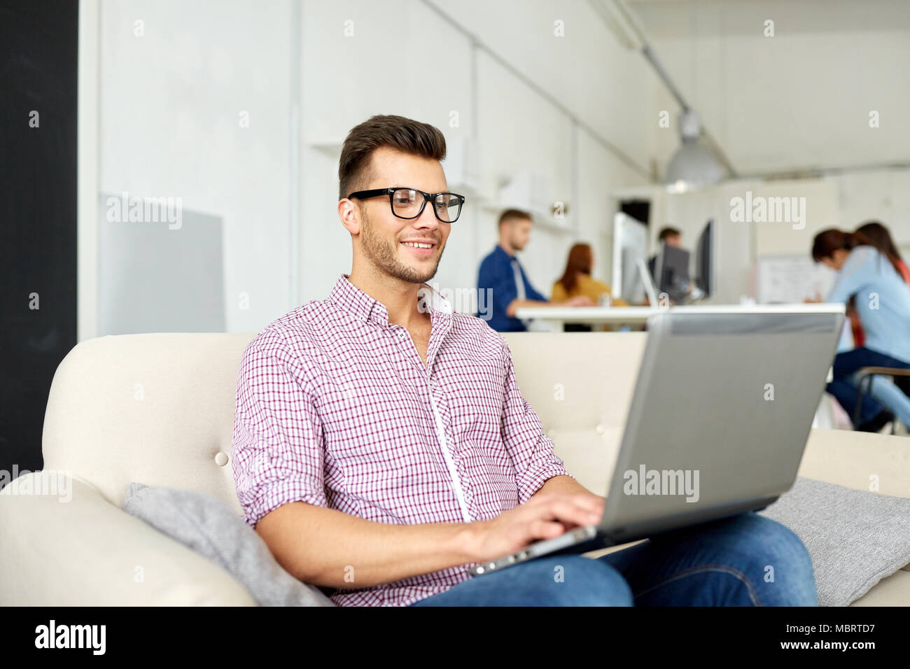 Uomo sorridente con notebook lavorando in ufficio Foto Stock