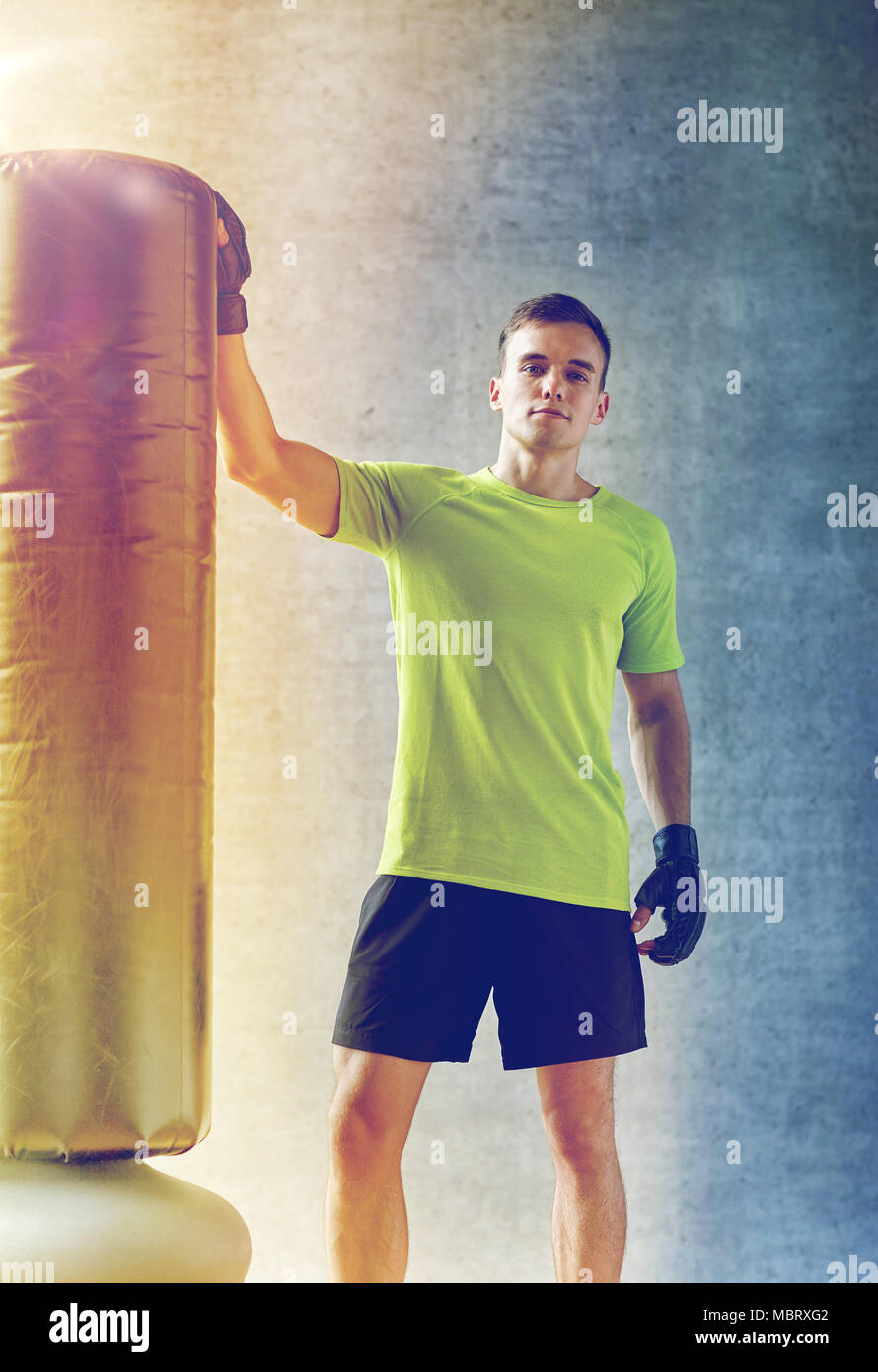 Uomo con i guantoni e sacco da boxe in palestra Foto Stock