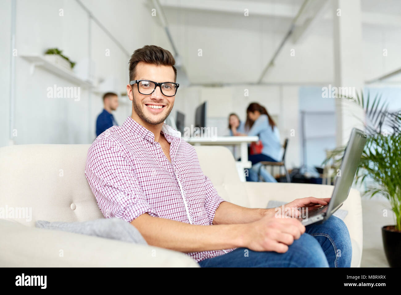 Uomo in occhiali con laptop lavorando in ufficio Foto Stock