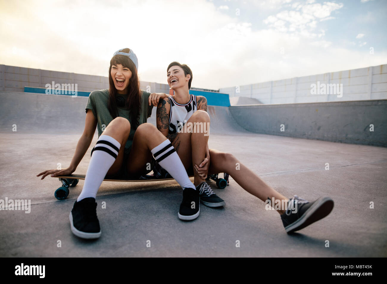 Donna skateboarders Ridere e divertirsi. Due pattinatori femmina amici ritrovo presso lo skate park. Foto Stock