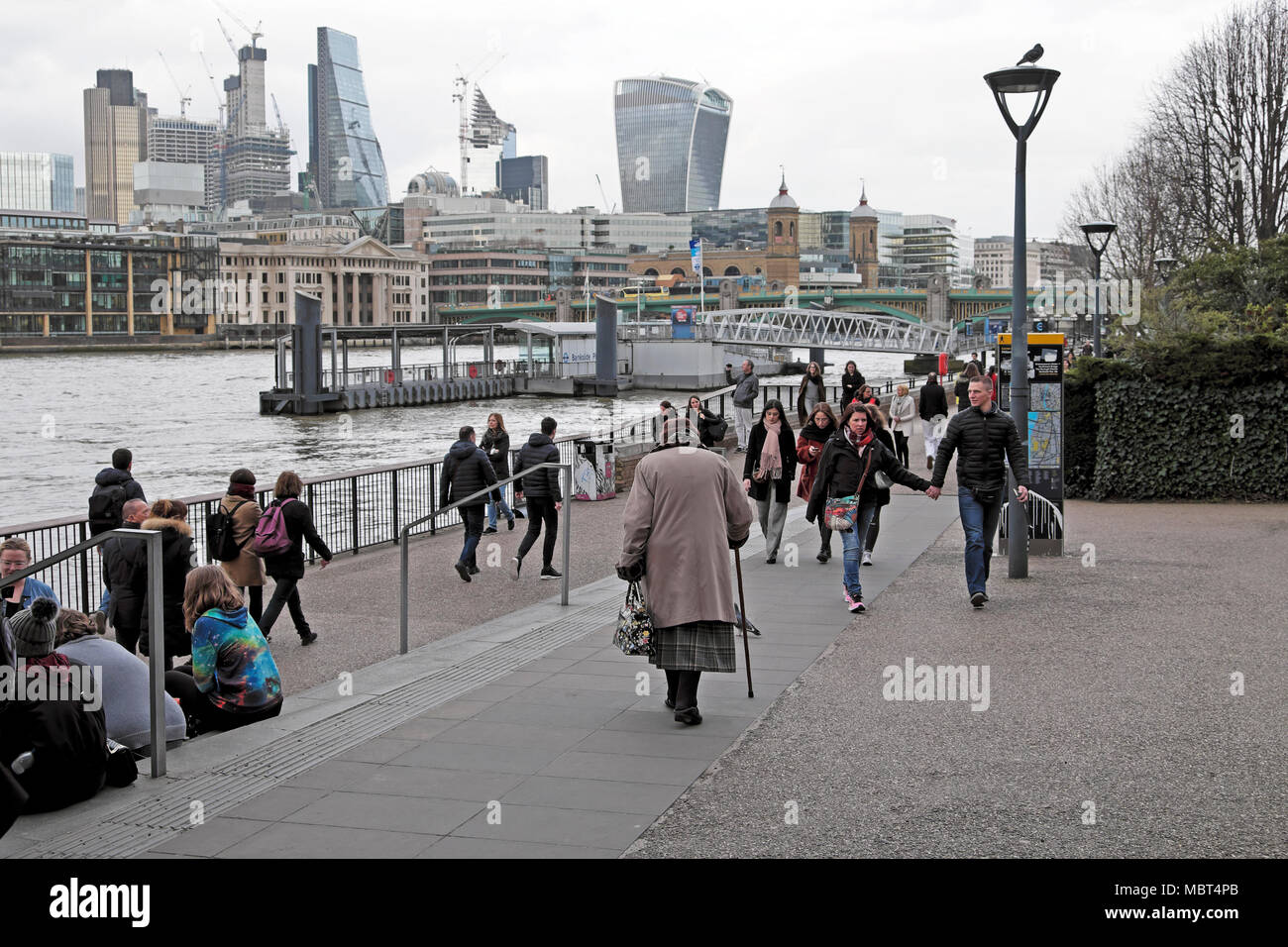 Vista del quartiere finanziario della City di Londra & vista posteriore della donna anziana con bastone da passeggio in mezzo ai turisti Bankside Londra UK KATHY DEWITT Foto Stock