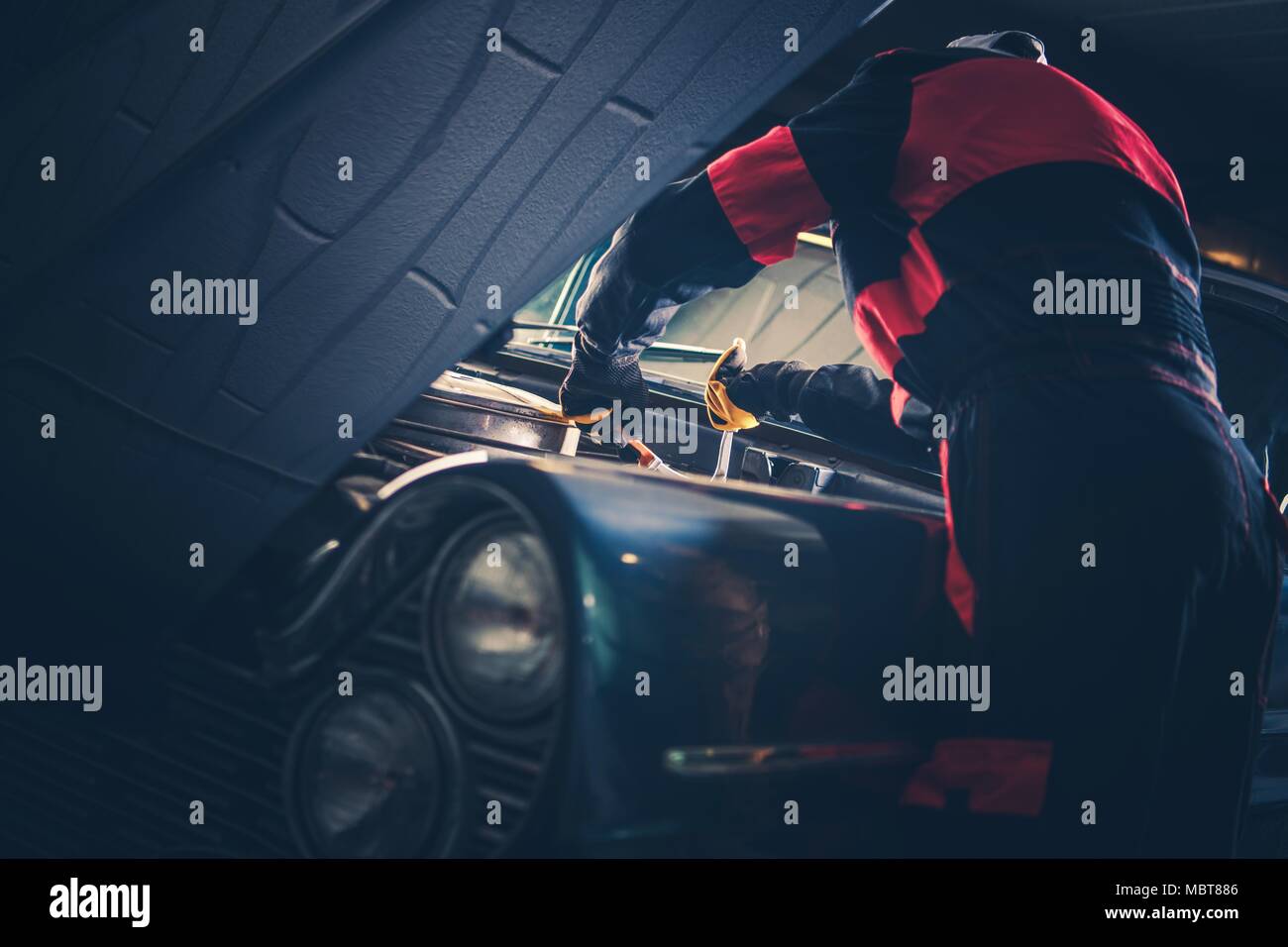 Auto classica restauro Fix. Uomini caucasici appassionato di veicoli vintage cercando di risolvere alcuni problemi con il suo American Classic Car motore a benzina. Foto Stock