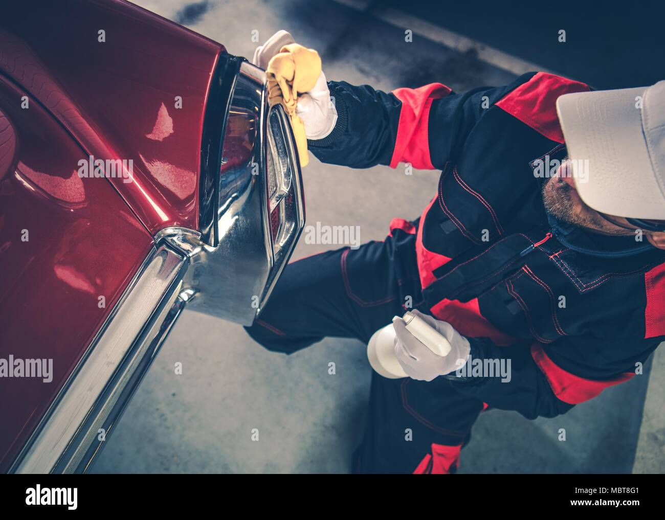 Uomini caucasici nella sua 30s che dettaglia il suo classico Auto con protezione corpo liquido. American veicolo da collezione. Profonda pulizia Automobile. Foto Stock