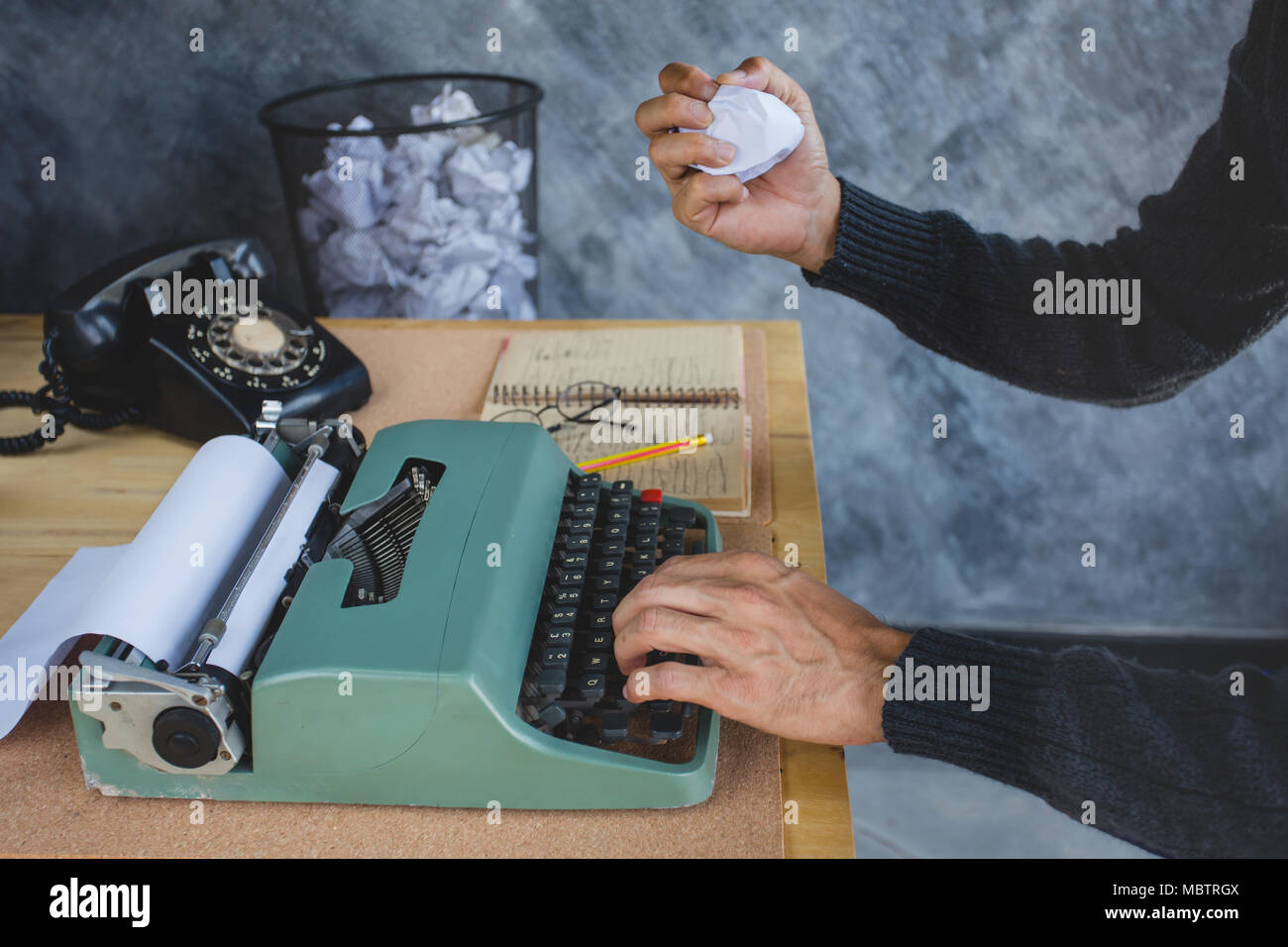 Un uomo che lavora molte sbagliato con i nastri inchiostratori per macchine da scrivere e lavorare a nuovo , un bin sfondo più carta mistage Foto Stock