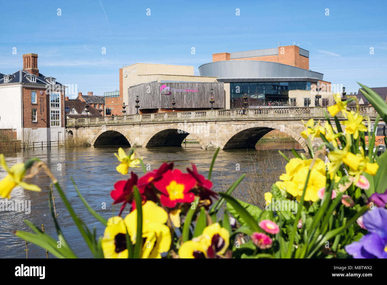 Il Welsh ponte sopra il fiume Severn con TheaterSevern al di là di fiori di primavera in fioriere. Shrewsbury, Shropshire, West Midlands, England, Regno Unito Foto Stock