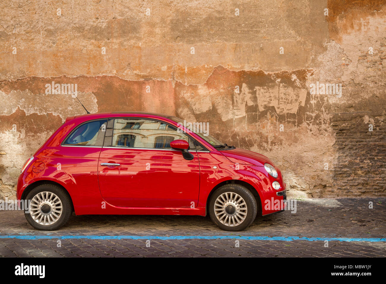 Rosso Fiat 500 automobile parcheggiata su una strada acciottolata a Roma, Italia, la linea blu indica un è un pagare per parcheggiare bay con parchimetri nelle vicinanze dove potete acquistare Foto Stock