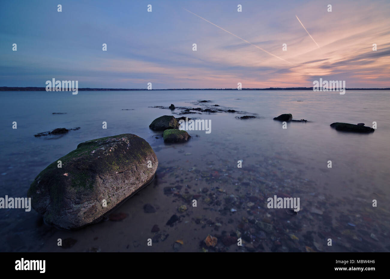Baltic seashore all'alba con grande roccia in primo piano (lunga esposizione) Foto Stock