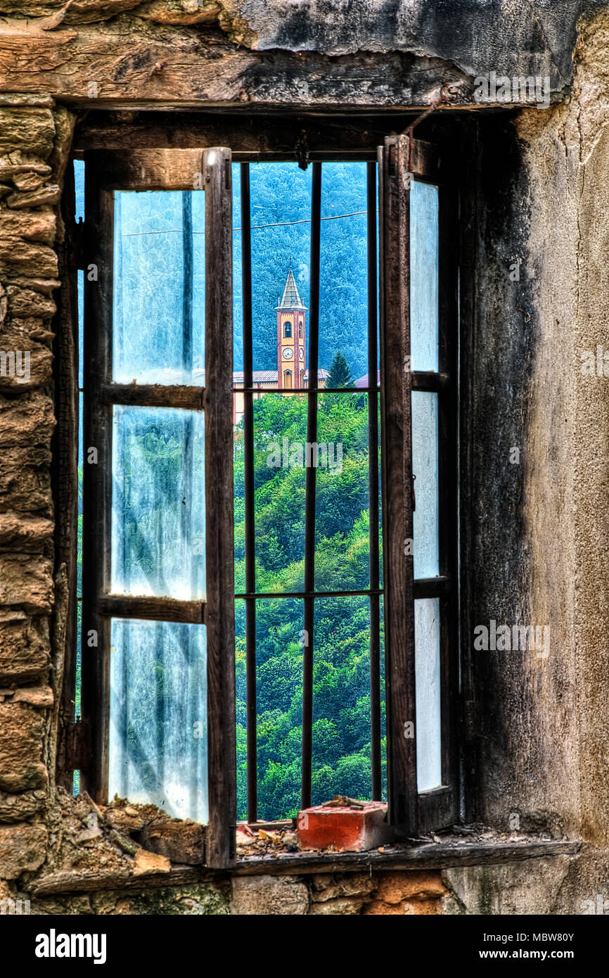 Il Cappello chiesa attraverso la finestra di una rovina abbandonati in Mindino, Garessio comune, Piemonte, Italia. Foto Stock
