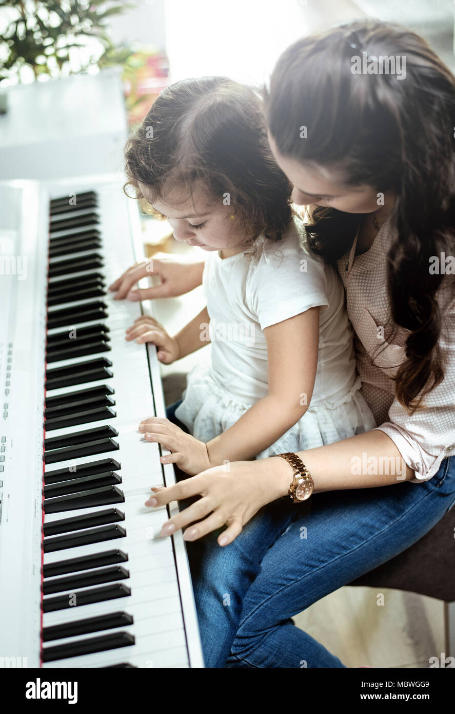 Giovane madre suonare il pianoforte con la sua piccola figlia Foto Stock