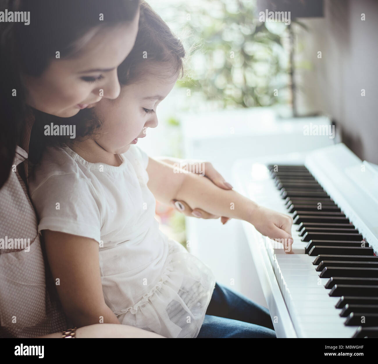 Mom insegnare la sua piccola figlia a suonare il piano Foto Stock