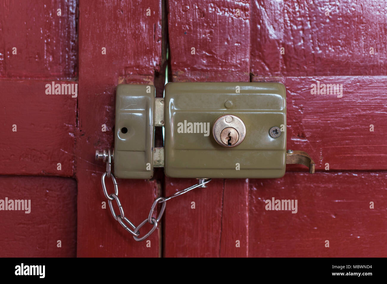 Vecchia serratura bloccata con la sua catena visto dall'interno di una  vecchia porta dipinta di rosso Foto stock - Alamy