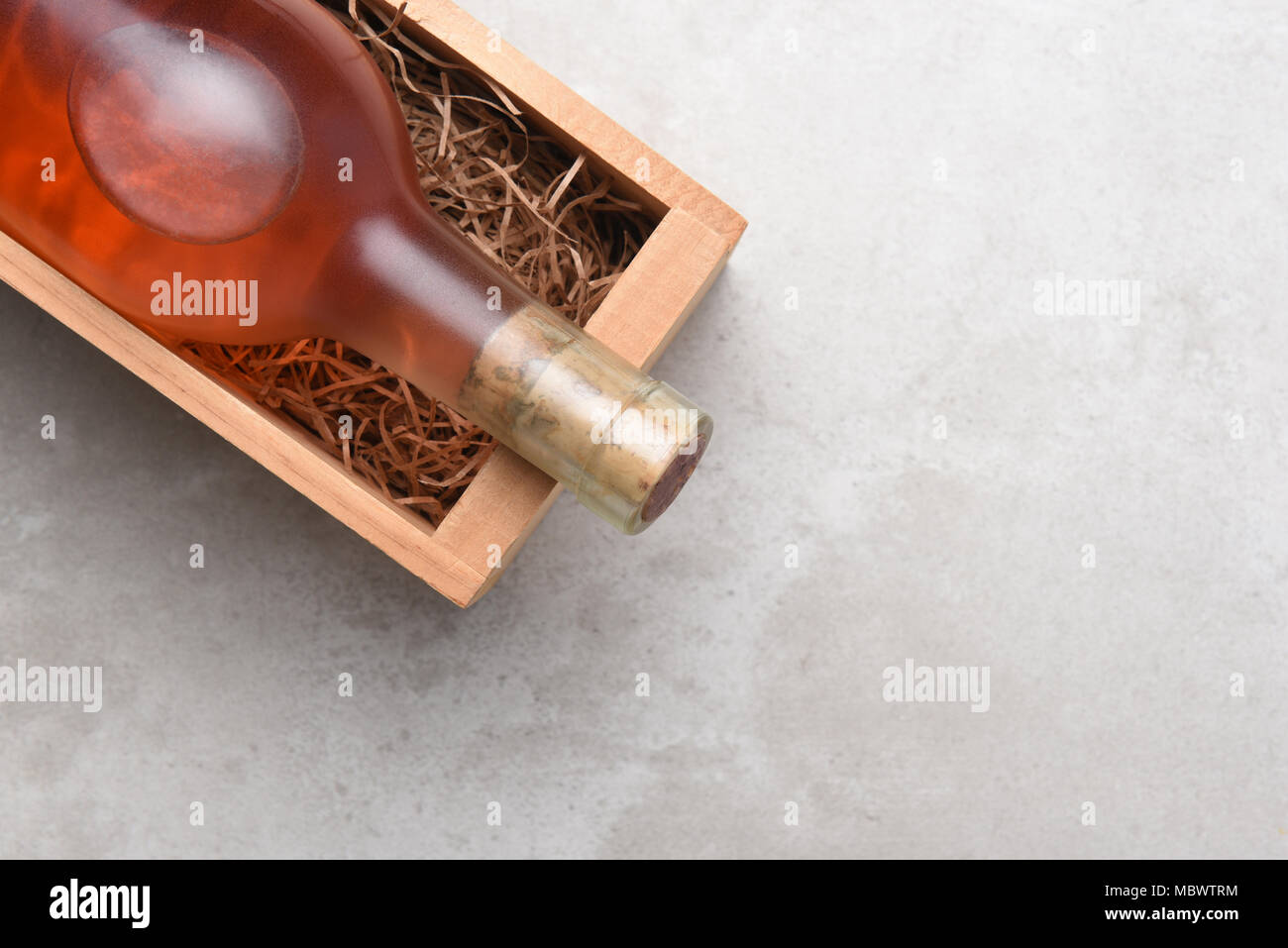 White Zinfandel, Blush vino: una bottiglia di vino rosato in una scatola di legno con imballaggio paglia. Elemento viene posizionato nell'angolo superiore destro con copia spazio. Foto Stock