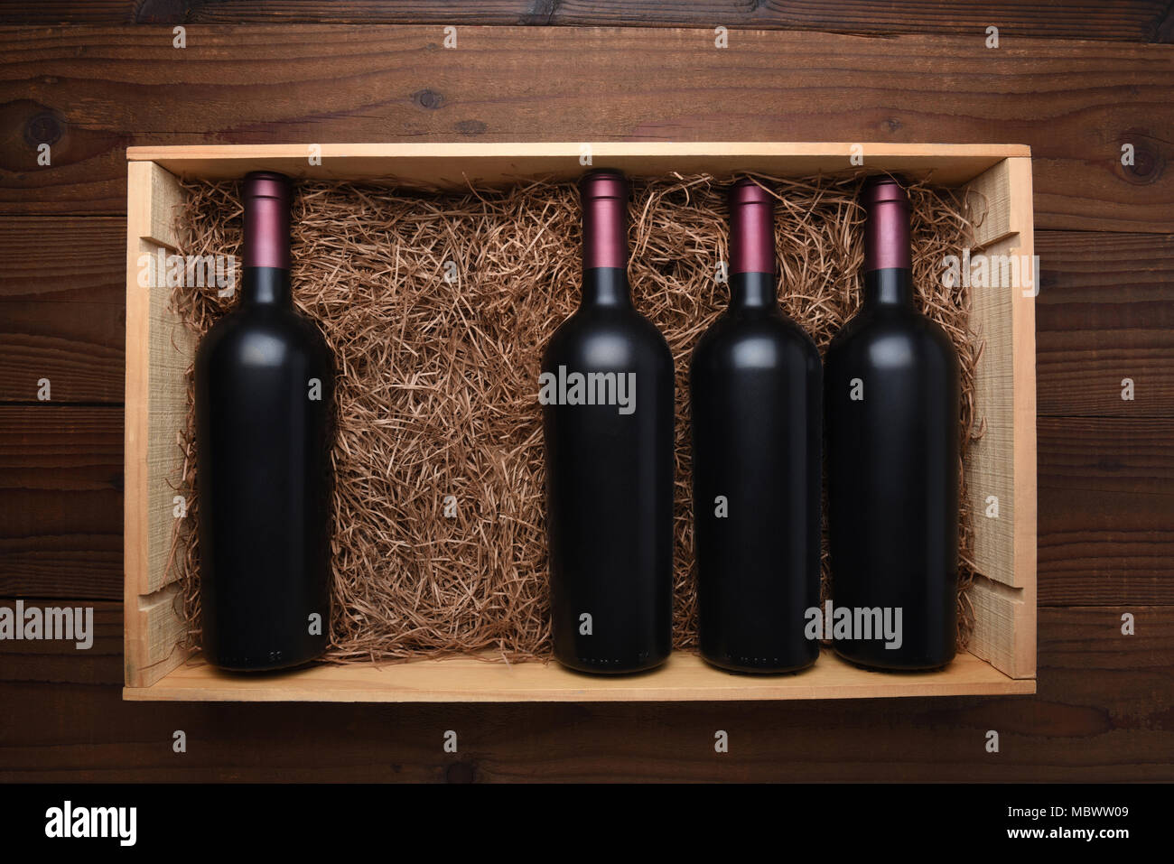 Caso di vino rosso: vista dall'alto di una scatola di legno di bottiglie di vino rosso con una bottiglia mancante, il caso è riempito con paglia di imballaggio. Foto Stock