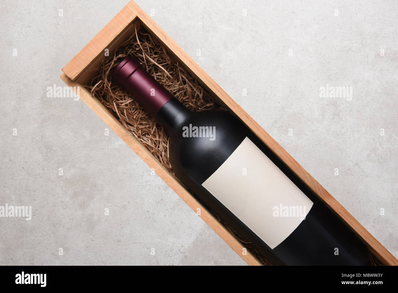 Vino rosso Bottiglia: una sola bottiglia di vino Cabernet in una scatola di legno con imballaggio paglia. Bottiglia è in corrispondenza di un angolo con copia spazio su entrambi i lati. Foto Stock