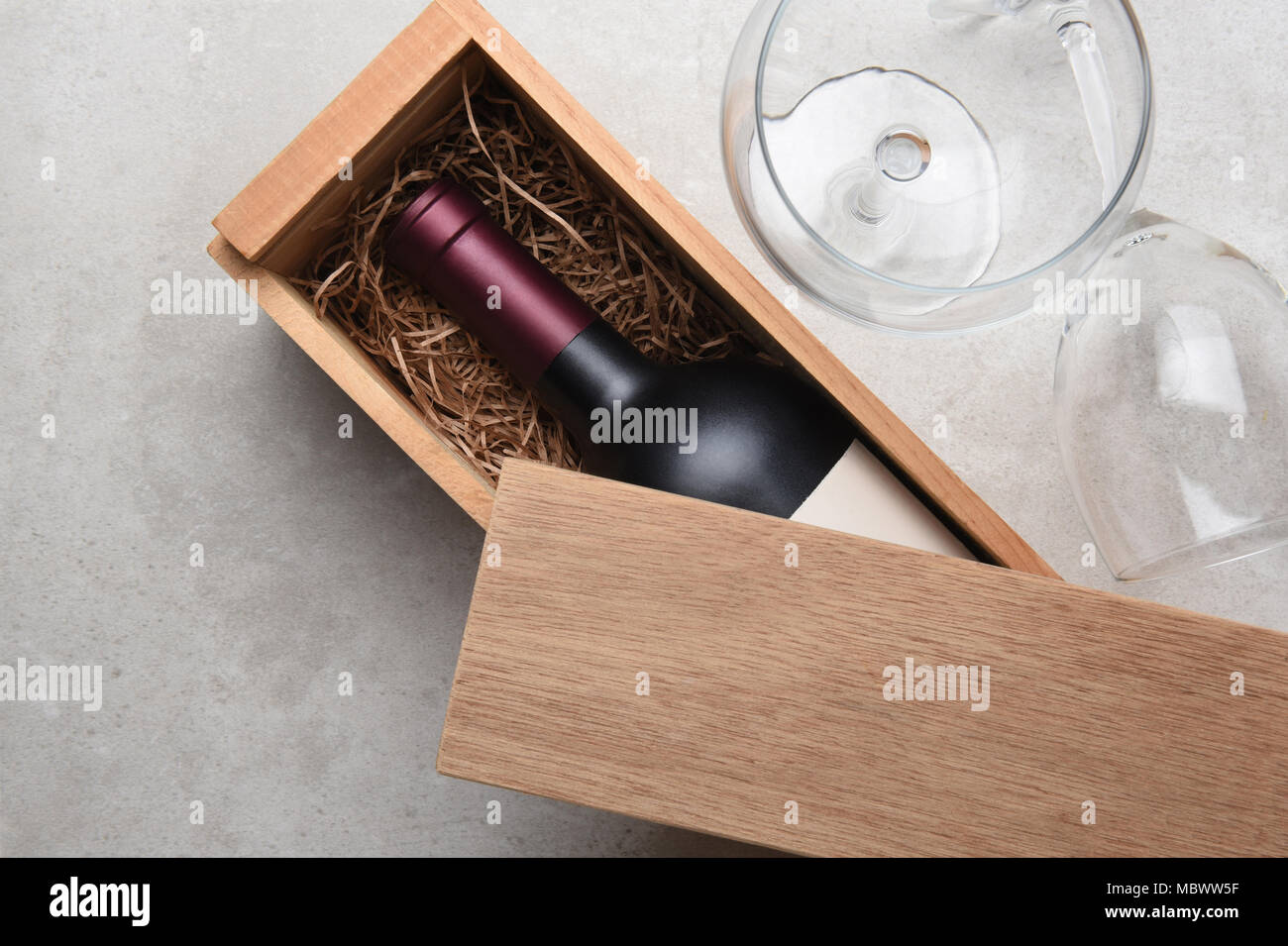 Vino rosso scatola: una sola bottiglia di Cabernet in una scatola di legno parzialmente coperto con il suo coperchio con due bicchieri vuoti. Foto Stock