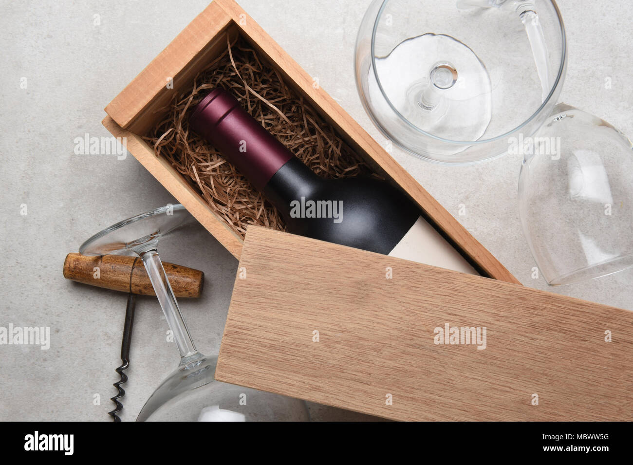 Vino rosso scatola: una sola bottiglia di Cabernet in una scatola di legno parzialmente coperto con il suo coperchio con bicchieri vuoti e un cavatappi Foto Stock