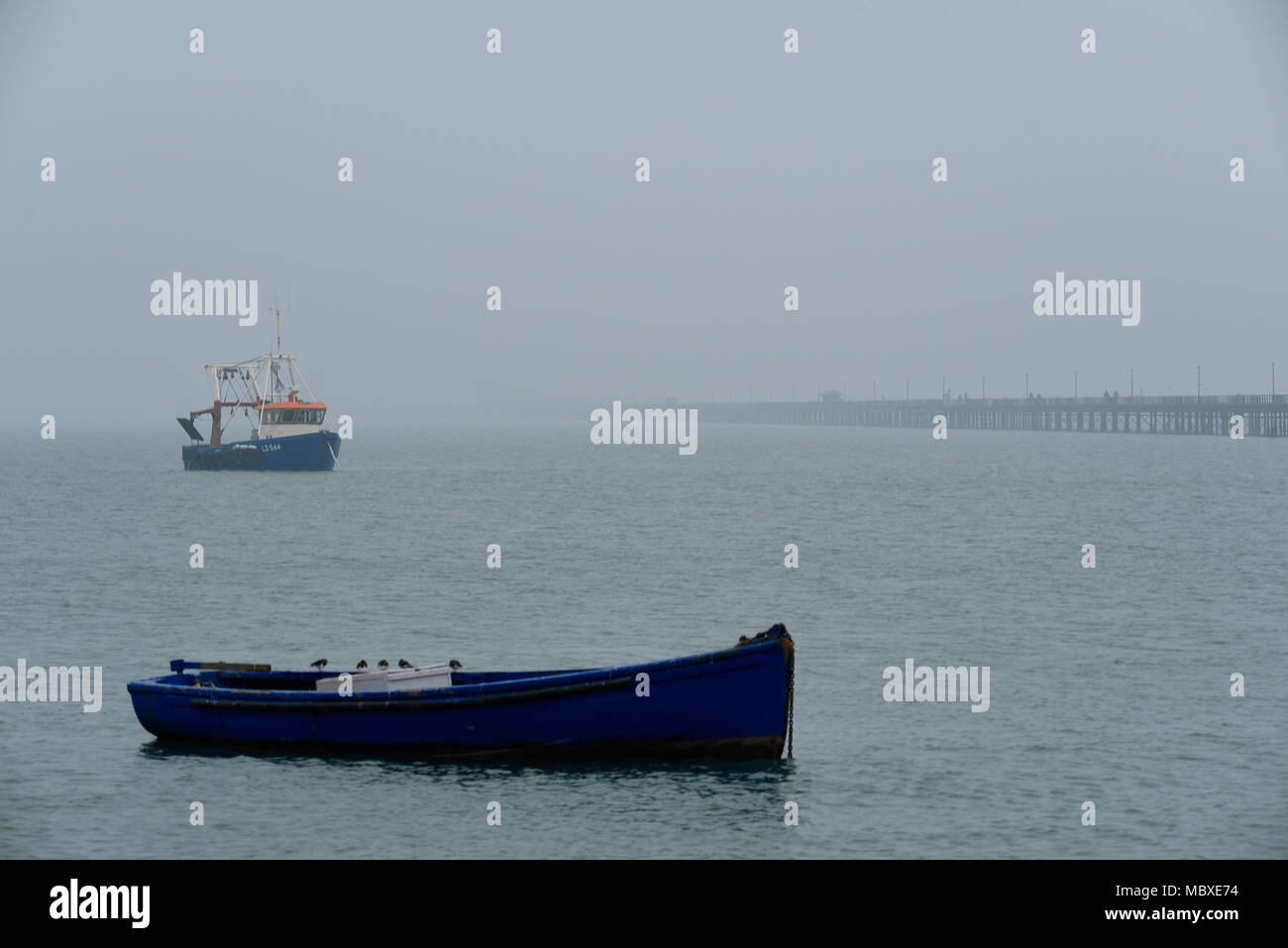 La nebbia e la foschia sopra Essex non scoraggiare gli escursionisti a passeggiare sul molo di Southend nel torbido estuario del Tamigi Foto Stock