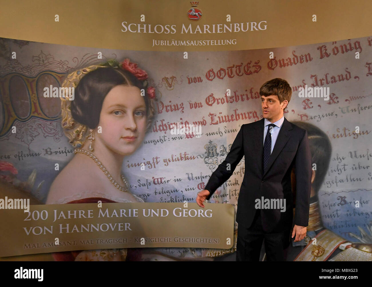 12 aprile 2018, Pattensen, Germania: Ernst August Junior di Hannover in piedi di fronte al '200 anni Marie e Goerg di Hannover" mostra banner presso il Castello di Marienburg. La mostra avrà inizio sabato 14 aprile, ed è dedicato alla Regina Maria il cui duecentesimo compleanno sarà in quel giorno. Foto: Holger Hollemann/dpa Foto Stock