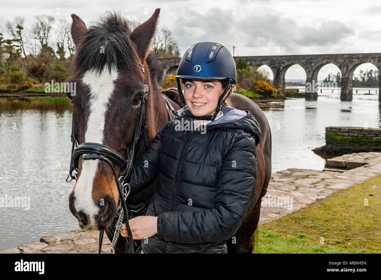 Ragazza con il suo cavallo con Ballydehob 12 il ponte di arco in background, Ballydehob, County Cork, Irlanda con copia spazio. Foto Stock