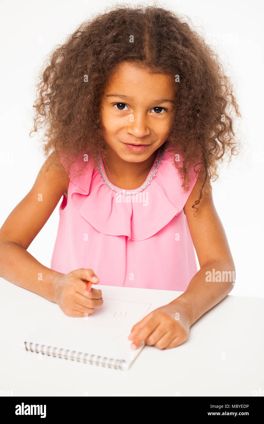 L'istruzione. Close up ritratto di African bambina è seduta al tavolo con un notebook per disegno, isolati su sfondo bianco Foto Stock