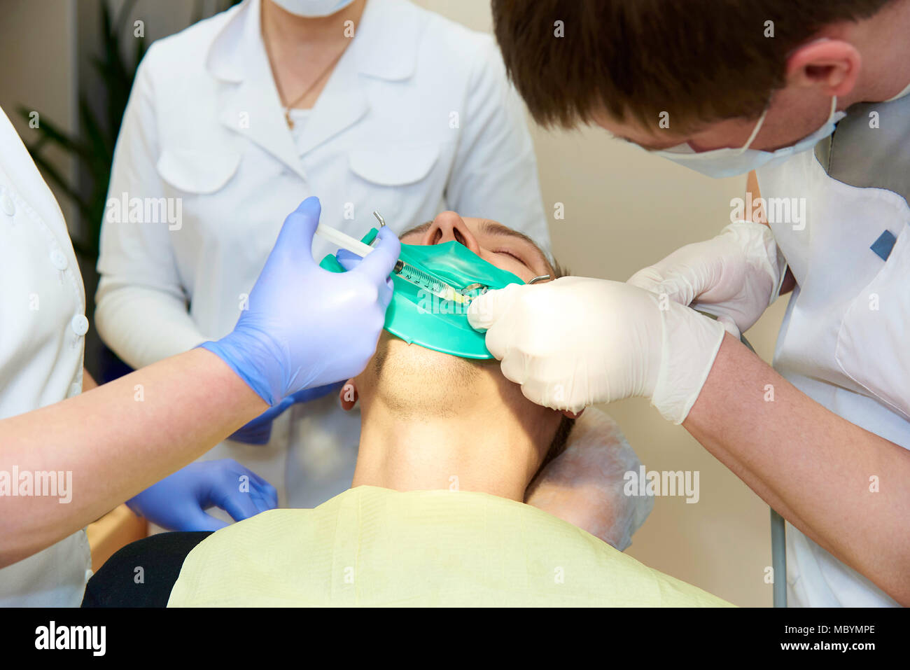 Un lattice piastra atta ad isolare il dente da trattare dal resto della cavità orale durante il trattamento. Il dentista fa iniezione di anestetico. Foto Stock