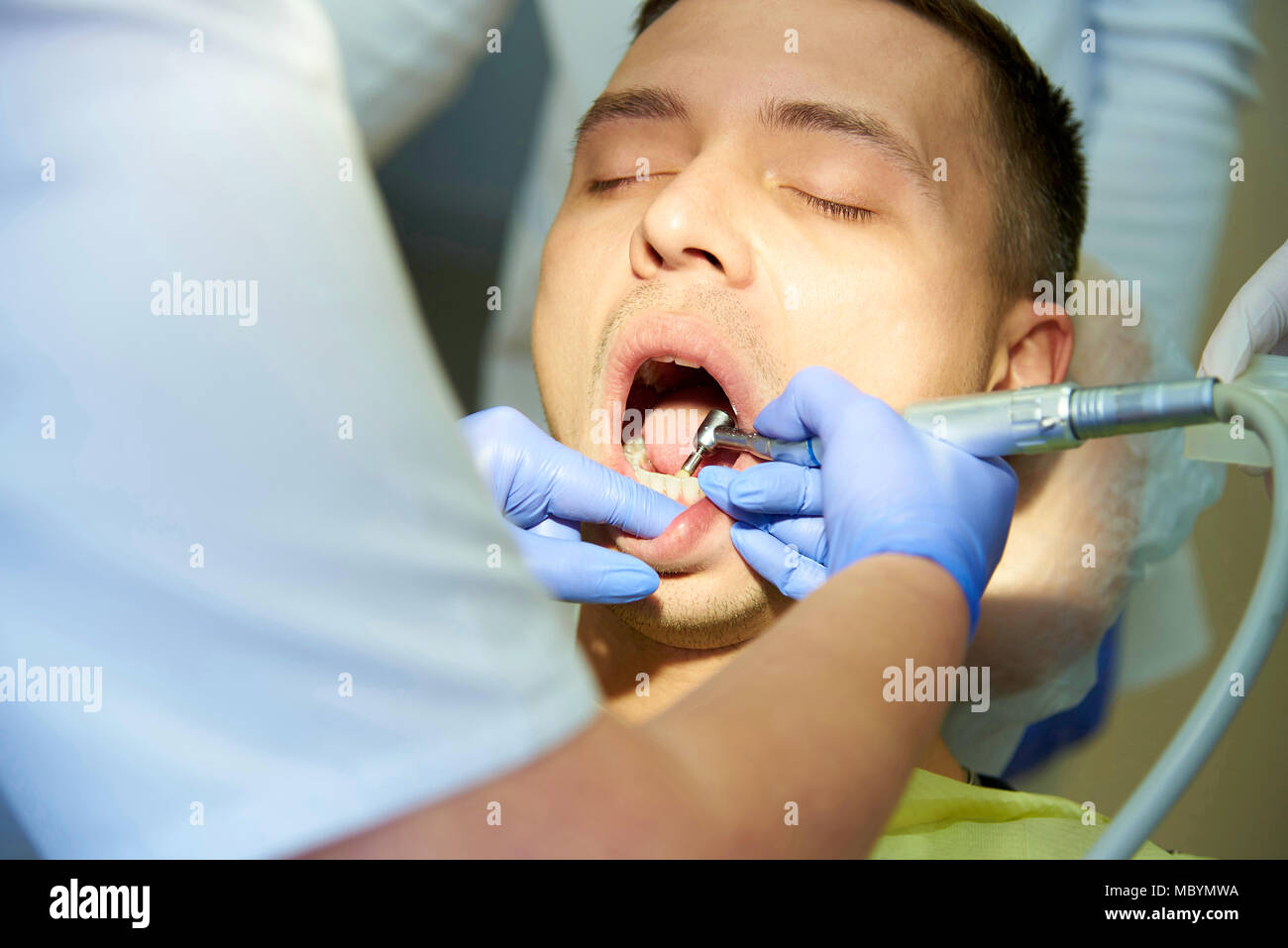 Un giovane uomo con gli occhi chiusi è il trattamento di denti da un dentista. Foto Stock