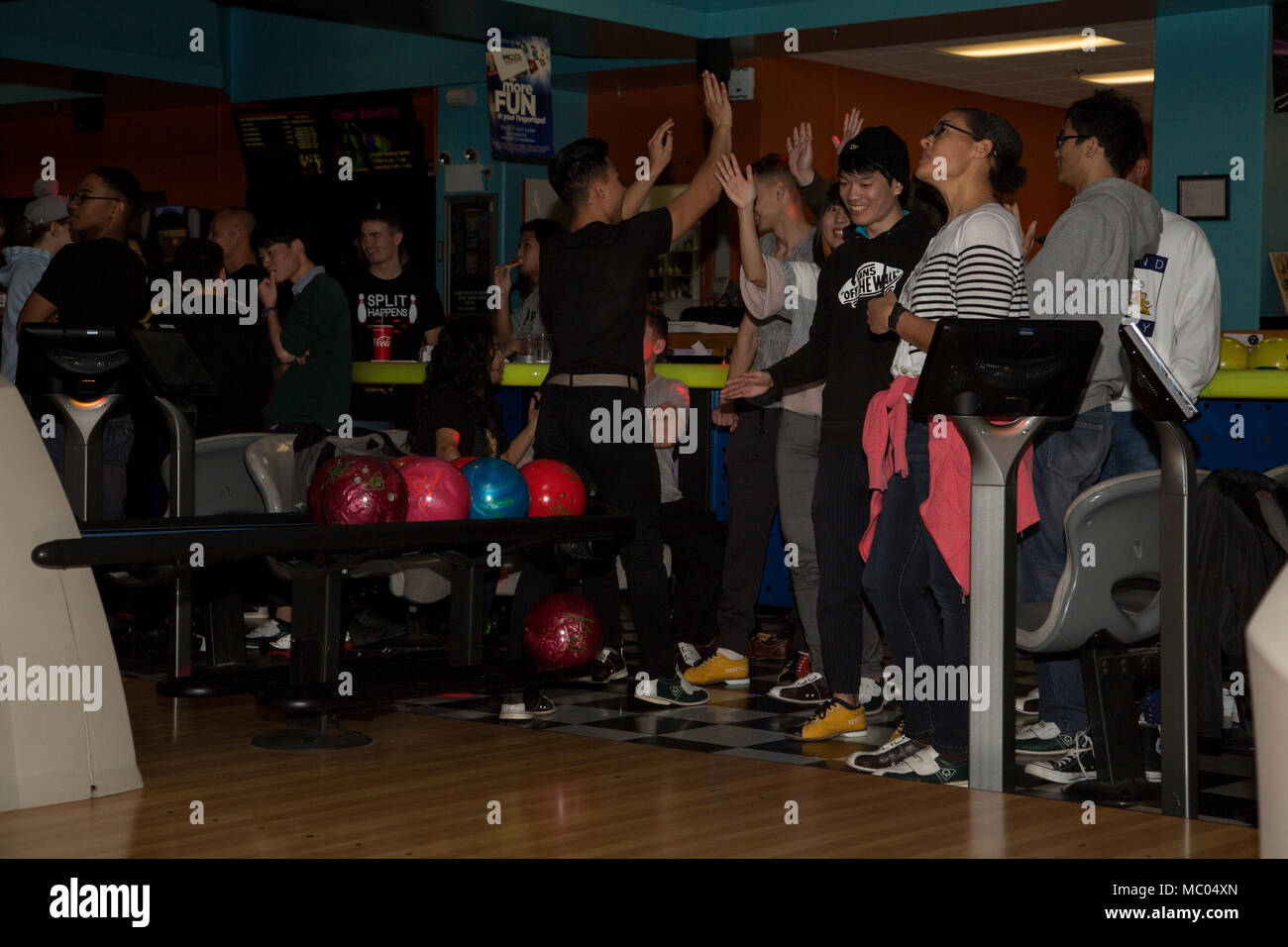 CAMP FOSTER, Okinawa, Giappone - Gli studenti dell Università di Okinawa celebrare uno sciopero con un organo di servizio 13 gennaio presso la pista da bowling a bordo Camp Foster, Okinawa, in Giappone. Ventotto membri di servizio e gli studenti si sono riuniti per la vaschetta e creare amicizie al Camp Foster Bowling. Battendo il cinque e saluti sono stati elargiti ai giocatori che hanno colpiti parti di ricambio e di scioperi. (U.S Marine foto di Caporale Tayler P. Schwamb) Foto Stock