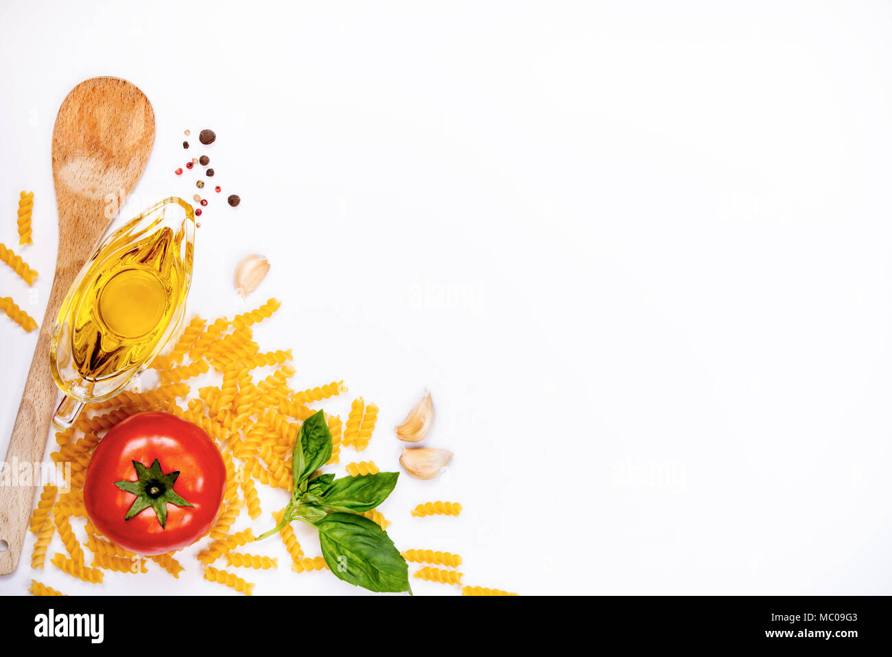 Vista dall'alto di ingredienti per la pasta su sfondo bianco - materie fusilli, basilico fresco, 4 spicchi di aglio, olio di oliva e mature tomatoe. Il cibo italiano concetto. Copia Foto Stock