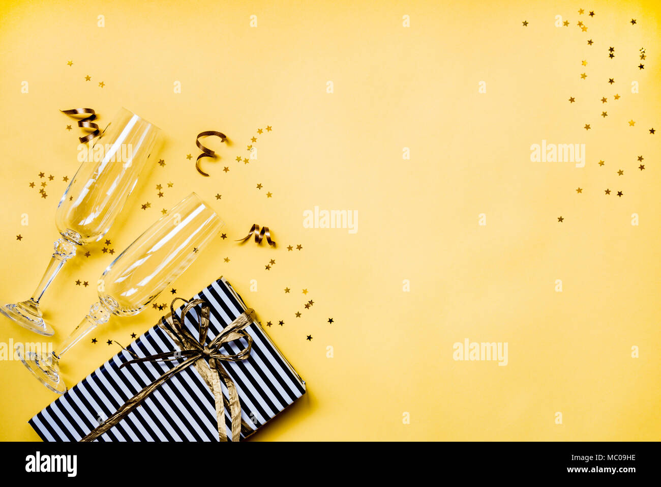 Celebrazione di sfondo - vista dall'alto di due azzuro bicchieri di champagne, un regalo avvolto in bianco e nero a strisce di carta, nastri e a forma di stella gold Foto Stock