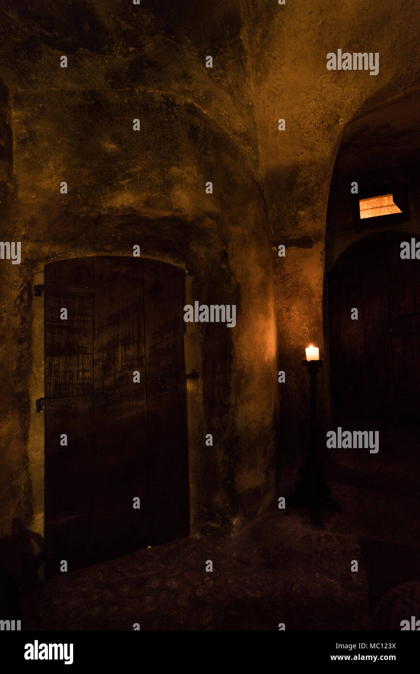 Scuro dello sfondo medievale con una massiccia porta di legno e la candela accesa in una stanza dim, Santo Stefano di Sessanio; Abruzzo; Italia; L'Europa Foto Stock