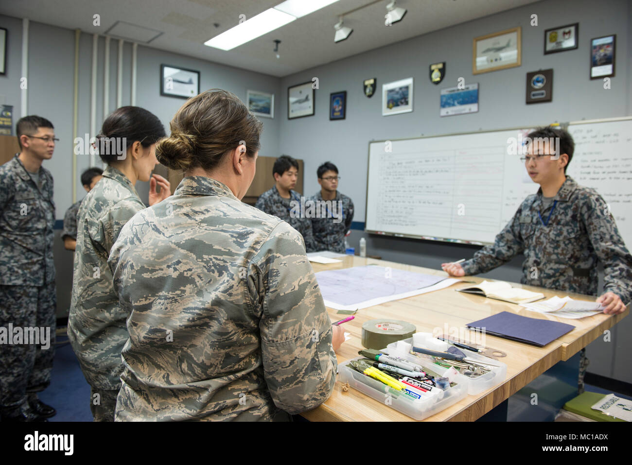 Un Japan Air Self Defense Force Stati dà una missione breve di colleghi JASDF dei membri e la loro forza aerea degli Stati Uniti omologhi gen. 11, 2018 a Kadena Air Base, Giappone. La scambio bilaterale con JASDF membri chiave aiuta i giocatori a prepararsi per il prossimo esercizio, far fronte nord. (U.S. Air Force foto di Senior Airman Jessica H. Smith) Foto Stock