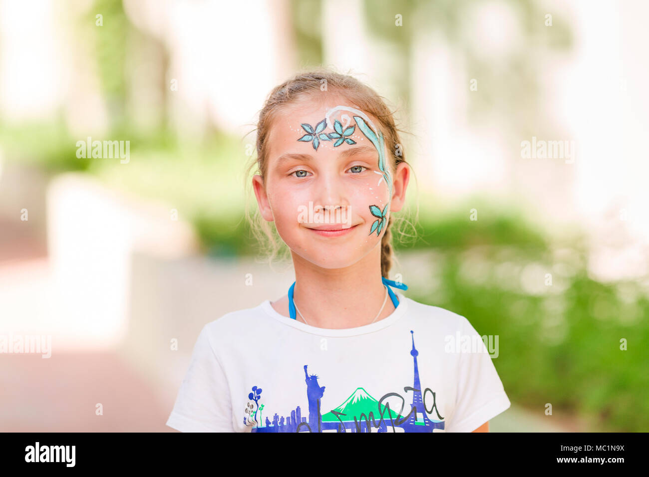 Felice bambina con la faccia tinta di arte nel parco. Bambino il compleanno masquerade party divertirsi, ridere. Intrattenimento e vacanze. Foto Stock