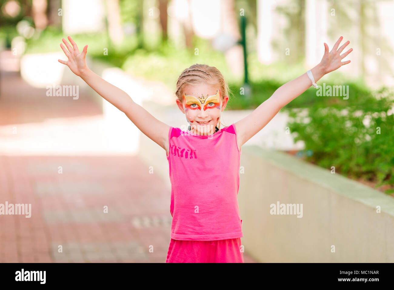 Felice bambina con la faccia tinta di arte nel parco. Bambino il compleanno masquerade party divertirsi, ridere. Intrattenimento e vacanze. Foto Stock