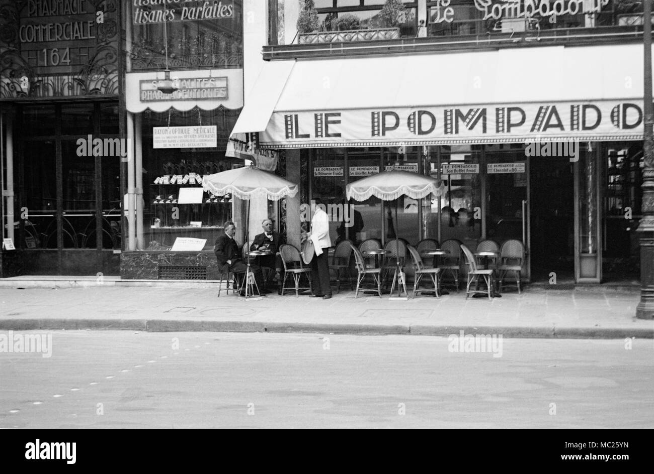 Fotografia in bianco e nero prese nel 1934 a Parigi, Francia. Mostra le Pompadour Cafe, con gli uomini e bere, con cameriere che serve loro. Foto Stock