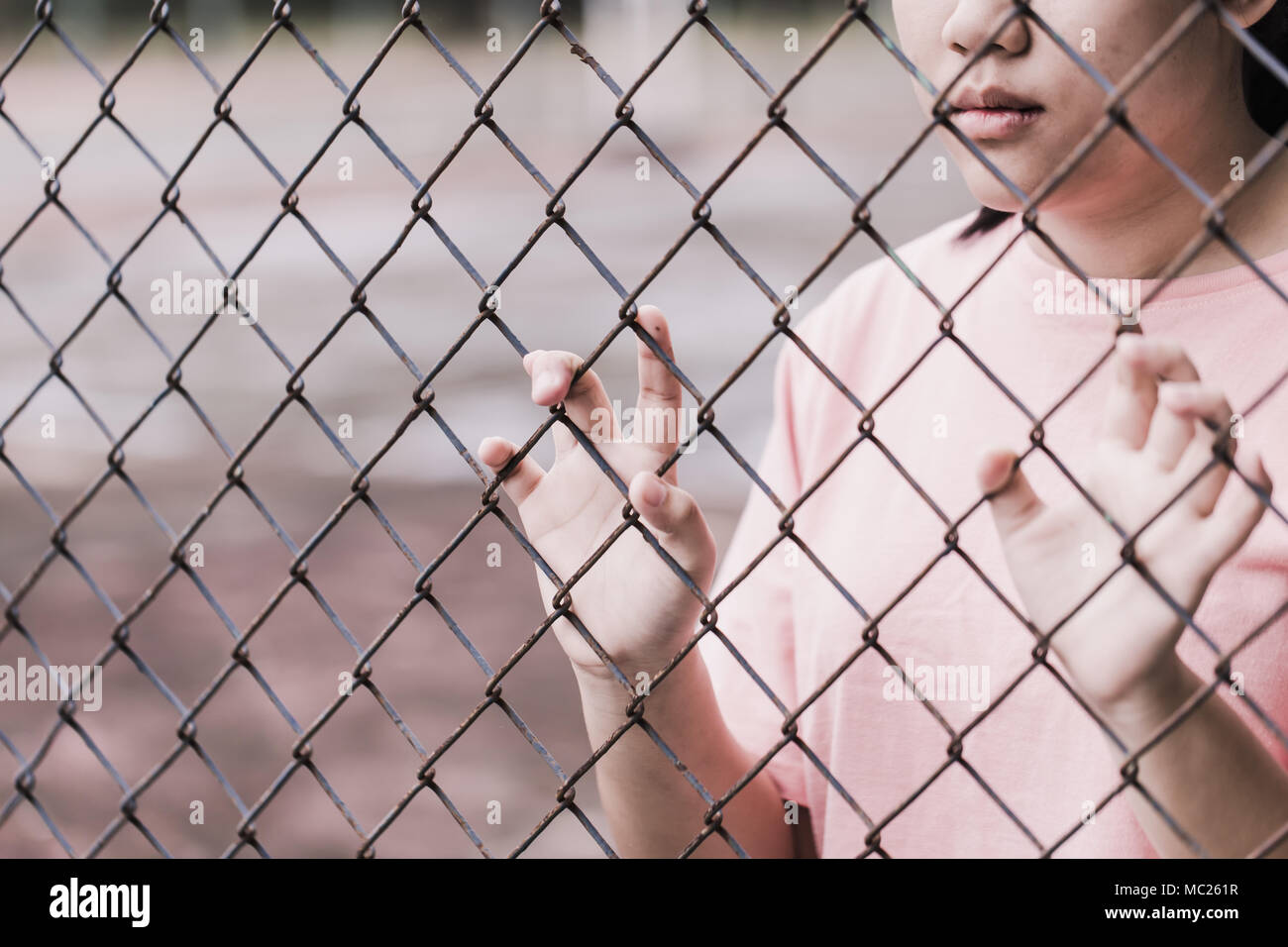 Teen dietro la gabbia o Donna imprigionato, infelice ragazza triste mano disperata di recinzione in carcere in carcere, non libera e libertà Lotta teen concetto. Foto Stock