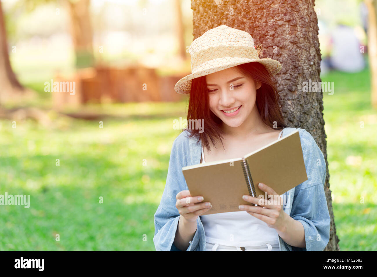 Bella donna asiatica libro di lettura nel parco in vacanza in auto-apprendimento Foto Stock