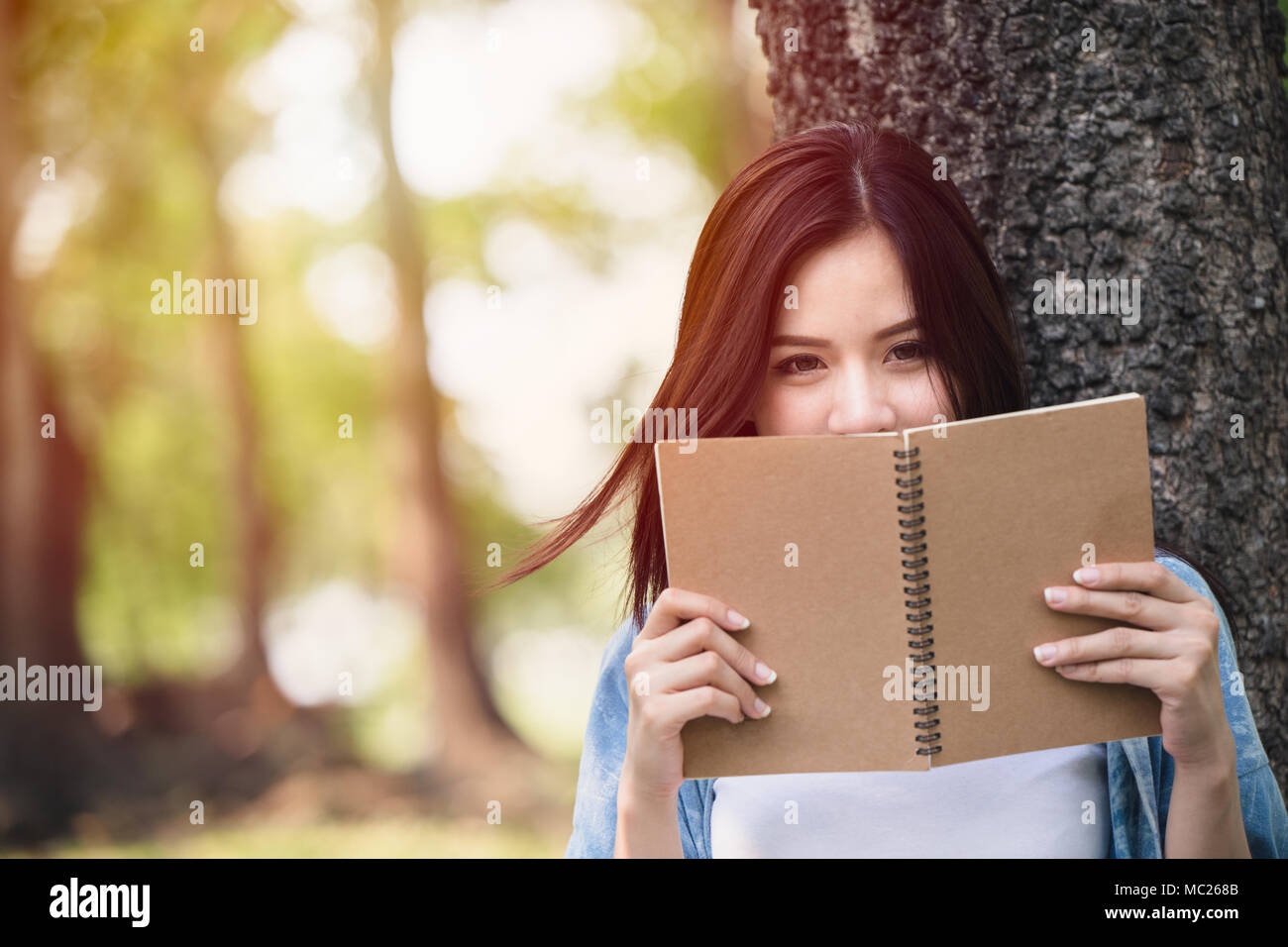 Bella donna asiatica la lettura nota prenota nel parco Foto Stock