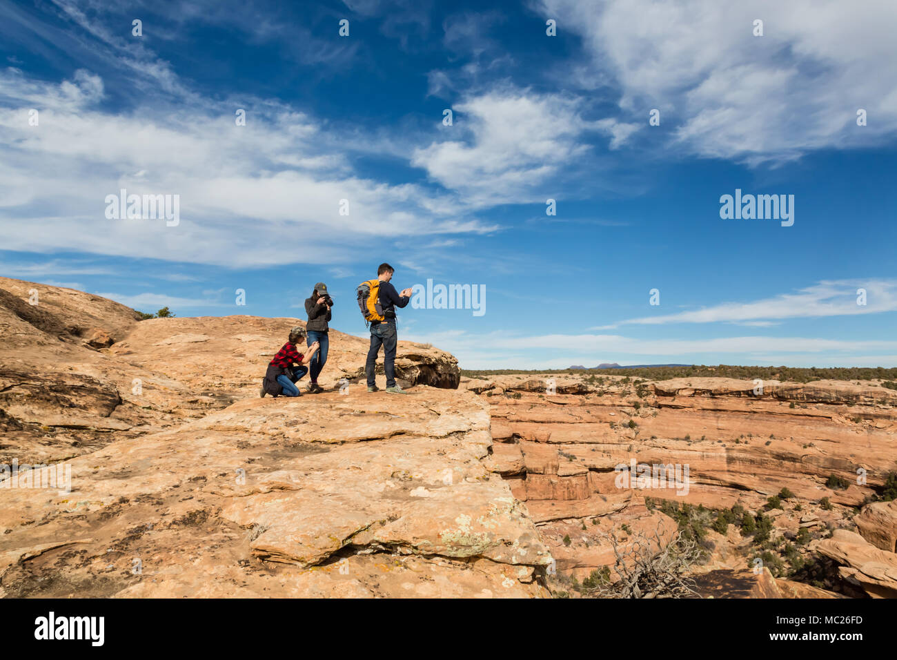 Una famiglia di tre escursionisti holding fotocamere fotografia lo spettacolare scenario di orsi orecchie monumento nazionale nel sud dello Utah. Foto Stock