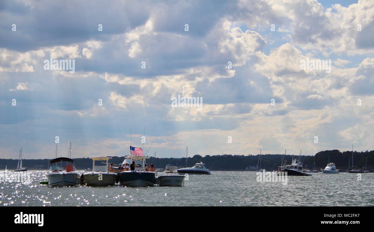 I raggi del sole a picco attraverso le nuvole si affaccia su quattro barche in una linea accanto a Rockport negli Newburyport bay. Foto Stock