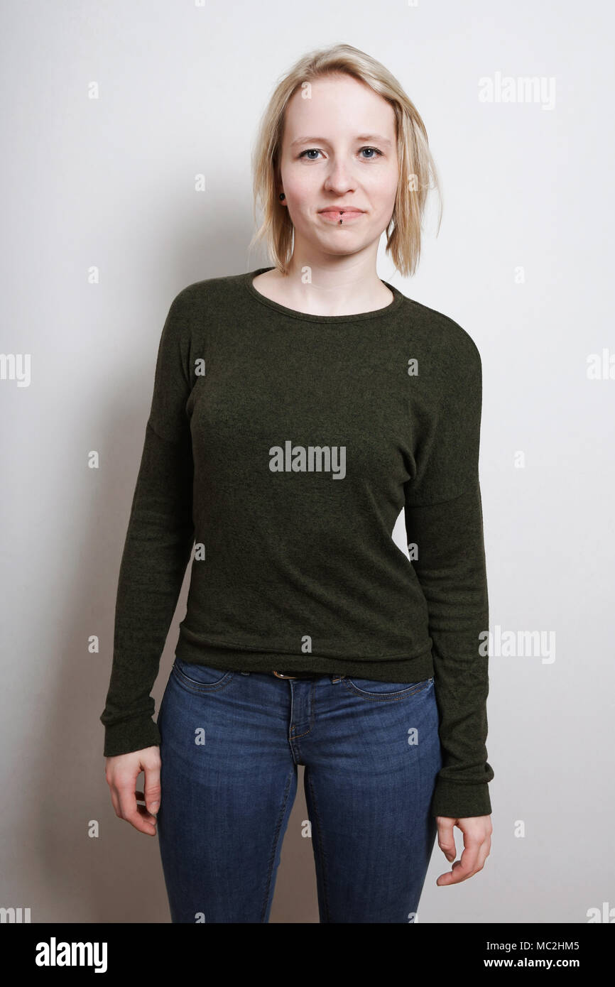 Tre quarti di lunghezza blue-eyed blonde fiducioso giovane donna in piedi Foto Stock