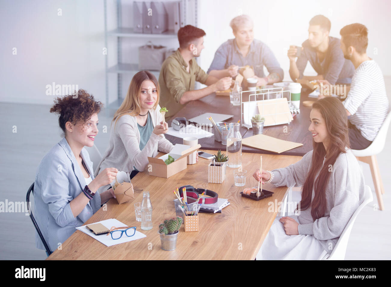 Persone sedute e parlando durante una pausa pranzo in ufficio Foto Stock