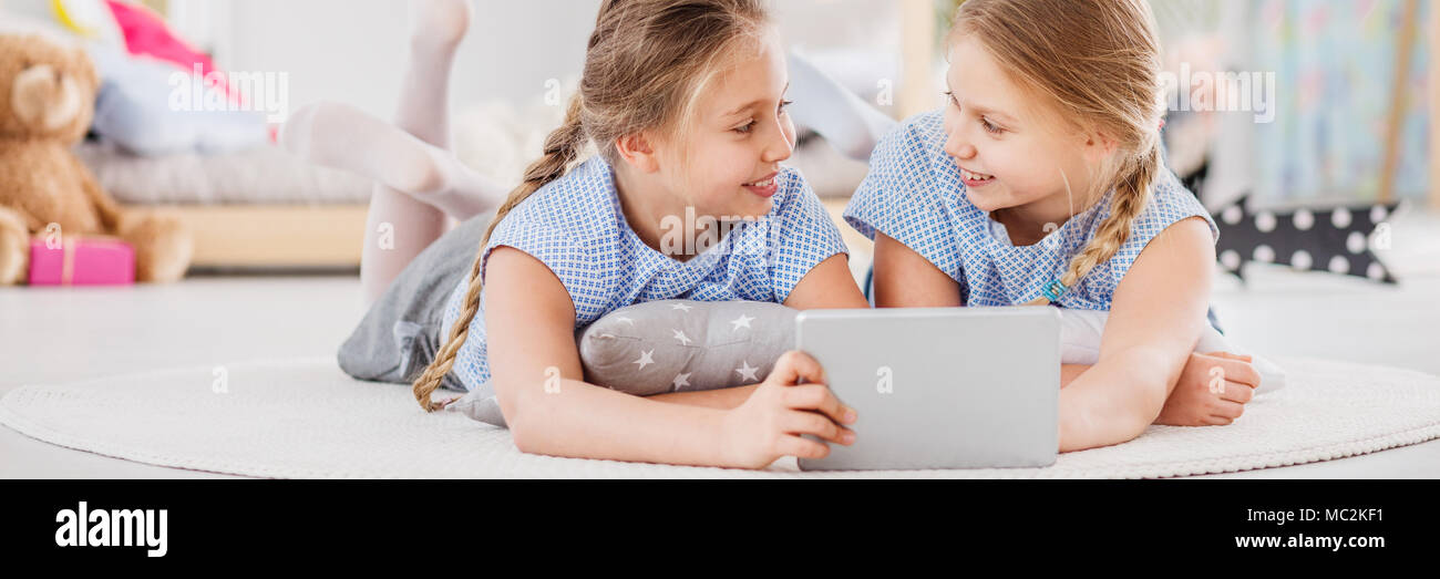 Migliori amici divertendosi insieme a sleepover, riproduzione di giochi mobile su un tablet in girly camera per ragazzi con i giocattoli Foto Stock